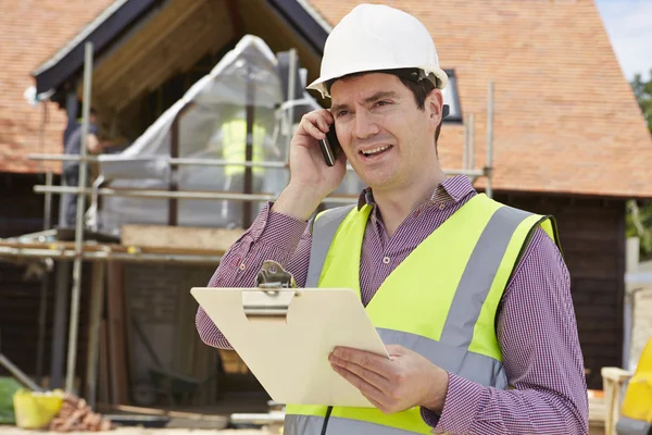 Arkitekt på byggnadsplatsen med mobiltelefon — Stockfoto