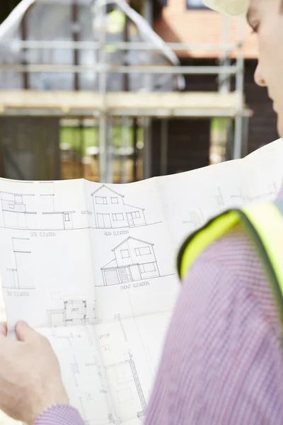 Architect op een bouwplaats kijken naar plannen voor huis — Stockfoto