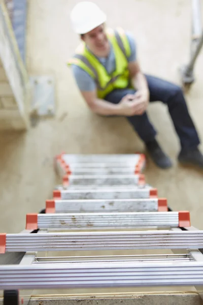 Trabalhador da construção que cai fora da escada e perna ferindo — Fotografia de Stock