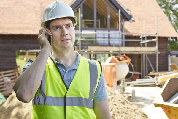 Byggnadsarbetare på byggnadsplatsen med mobiltelefon — Stockfoto