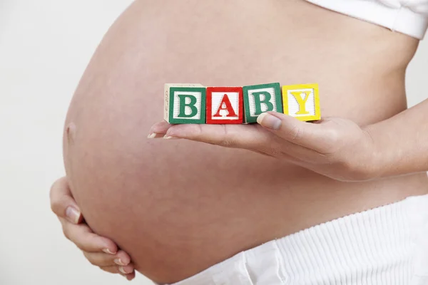 Pregnant Woman Holding Wooden Blocks Spelling Baby — Stock Photo, Image