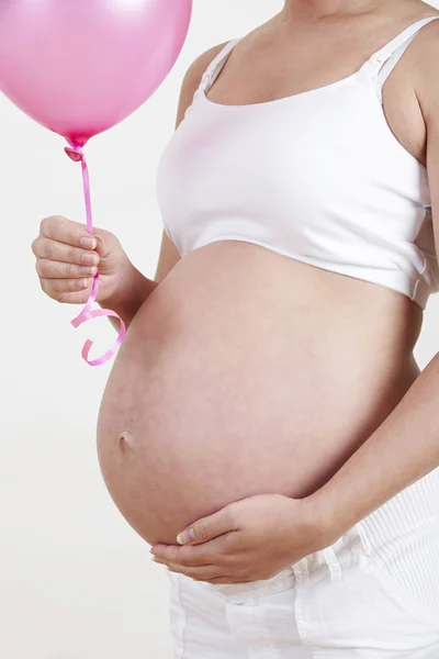 Nahaufnahme einer schwangeren Frau mit rosa Ballon — Stockfoto