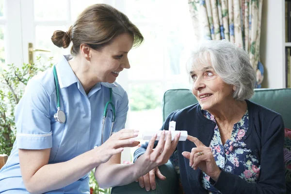 Krankenschwester berät Seniorin bei Medikamenten zu Hause — Stockfoto