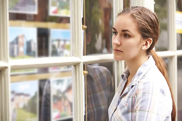 Jeune femme déçue regardant dans la fenêtre des agents immobiliers — Photo
