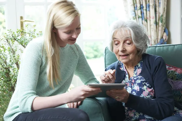 Büyükanne dijital tablet kullanmayı gösterilen torunu — Stok fotoğraf