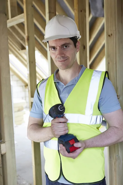 Constructor en el sitio de construcción que sostiene taladro inalámbrico — Foto de Stock