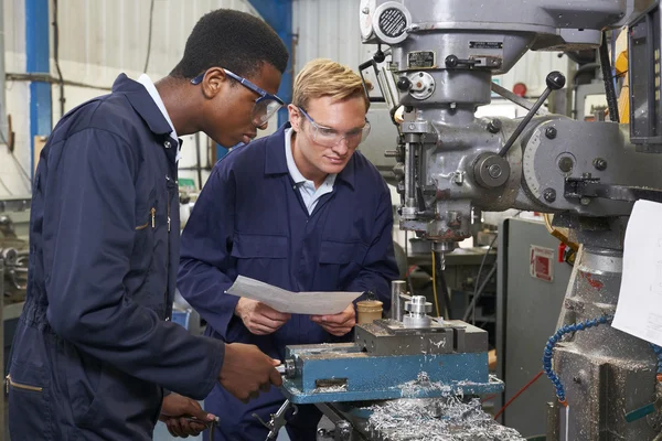 Ingegnere che mostra all'apprendista come usare il trapano in fabbrica — Foto Stock