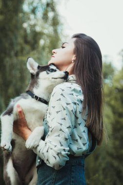 Genç ve güzel kız sevimli köpeğiyle oynuyor. 