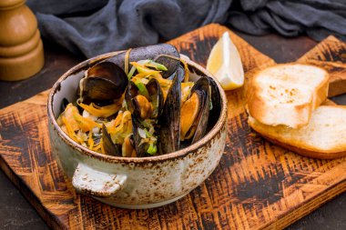 Mussels in wine sauce on the board with bread