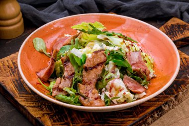 salad with duck on a white plate on the board