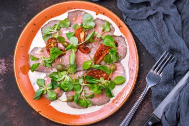 vitello tonato on a plate on dark stone table