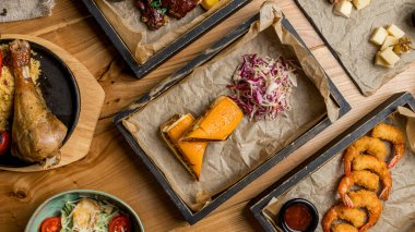 Assorted meat dishes. Burger, fried chicken breast, chicken Salad, potatoes in the country, pork ribs, turkey, wok, cheese plate on a wooden table