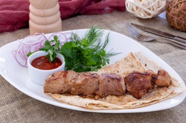 Kırmızı soğanlı domuz kebabı ve beyaz tabakta sos.