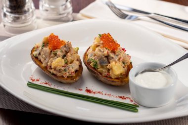 Kömürde kavrulmuş patatesler ve beyaz tabakta ringa balığı.