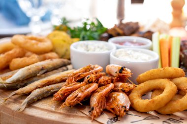 assorted beer snacks on a wooden board with sauces macro close up