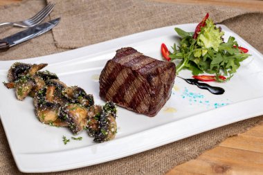 grilled Denver steak with grilled mushrooms on white plate