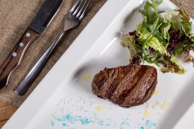 Beyaz bir tabakta ızgara biftek fileto.