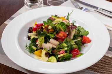 Beyaz tabakta domatesli yeşil sebze salatası.