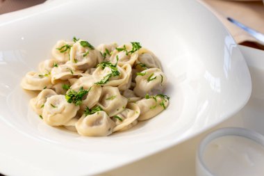 Ekşi kremalı hamur tatlısı ve beyaz tabakta otlar.