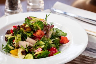 Beyaz tabakta domatesli yeşil sebze salatası.