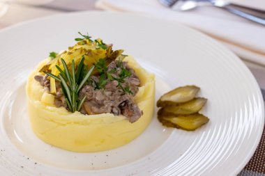 Stroganoff beyaz tabakta, yanında patates püresi var.