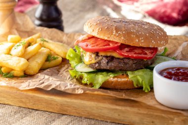 Et, domates, salata ve peynirli hamburger ve patates kızartması.
