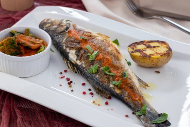 Limonlu kızarmış levrek ve beyaz tabakta sebze.