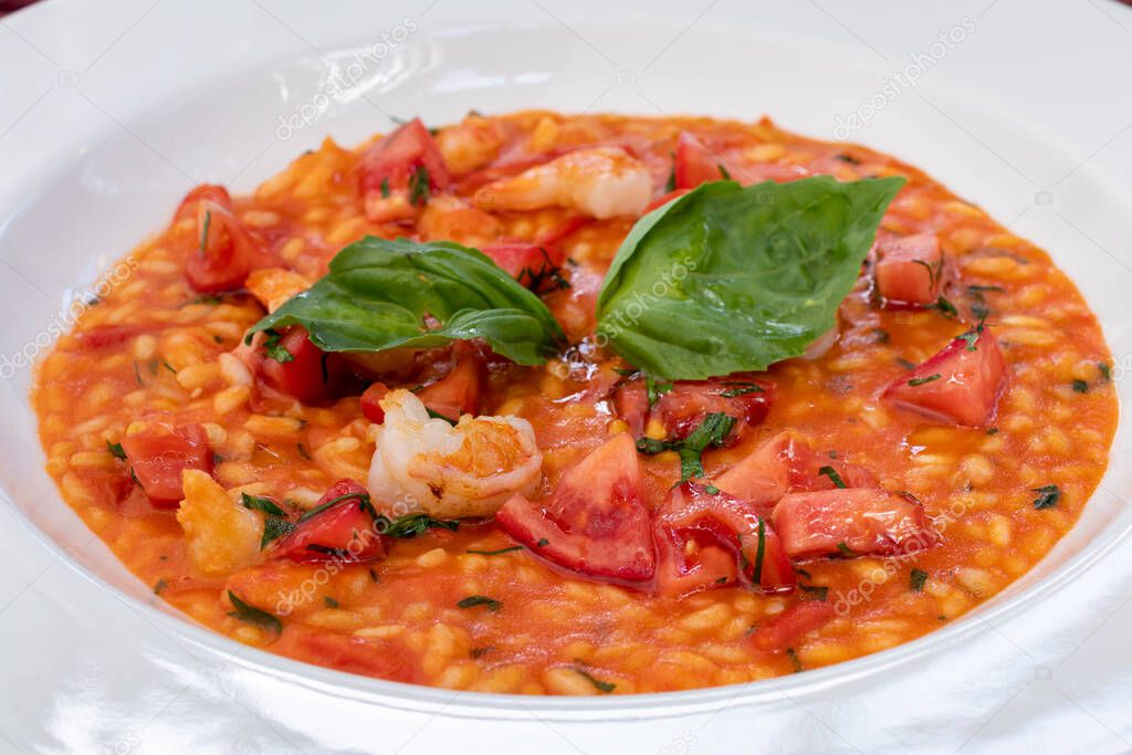 Risotto with shrimp and tomato sauce on white plate