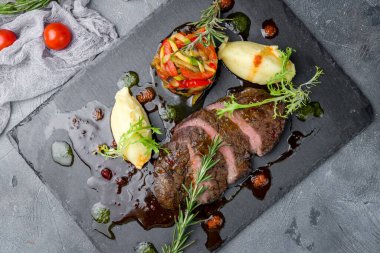 Izgara biftek fileto. Mignon gri masa manzaralı tabakta dilimlenmiş.