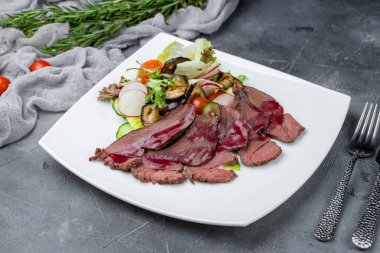 Gri masada kurutulmuş geyik eti ve sebze dilimlenmiş salata.