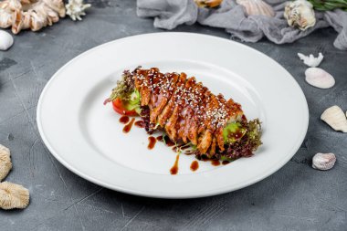 Sashimi yılanbalığı tabakta, yeşiller gri masada.