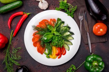 Koyu masa manzaralı bir tabakta taze sebzeleri dilimliyorum.