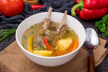Kuzu etli Shurpa Asya çorbası, patates ve havuç siyah masada beyaz kasede.
