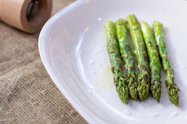 Beyaz tabakta dev kuşkonmaz ızgarası.