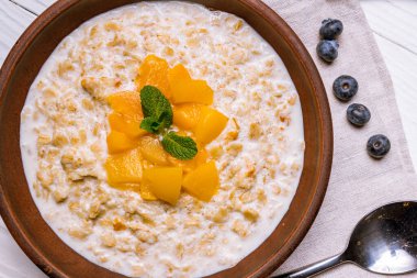 Meyveli yulaf ezmesi ve beyaz ahşap masa manzaralı sütlü nane şekeri.