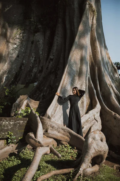 Brunette met lang haar poserend in een 700 jaar oude Banyan boom. Bali, Indonesië — Stockfoto