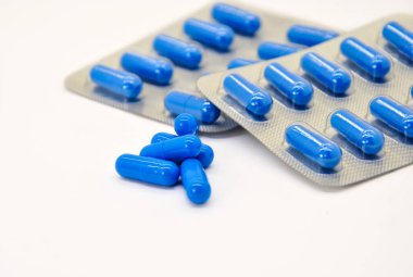 blue capsules in blister and without on a white background. blurred background and glare