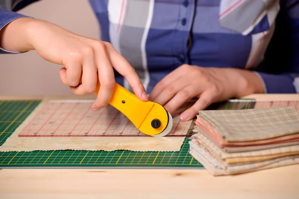 Close-up female hands cutting fabric with patchwork rotating cutter — Stock Photo, Image