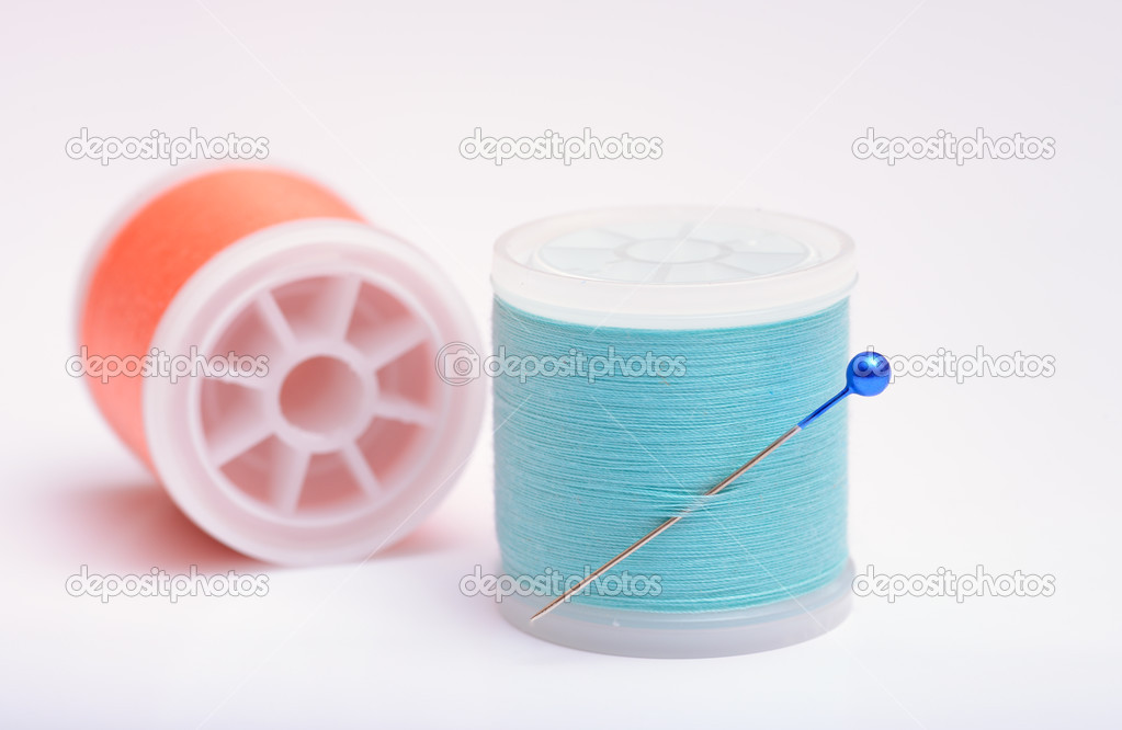 Isolated thread spools with pin on white background