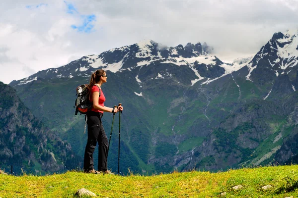 Young woman with backpack and trekking poles in mountains — Stock Photo, Image