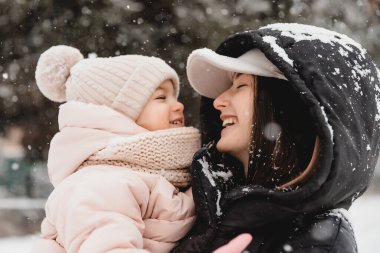 Sevgi dolu bir aile! Anne ve kız doğada karlı kış yürüyüşlerinde eğleniyor, gülüyor ve eğleniyorlar. Buz mevsimi.
