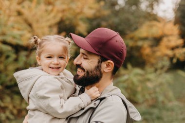 Mutlu baba-kız güzel bir sonbahar parkında yürürken oynuyorlar. Küçük kızıyla mükemmel bir hafta sonu babası. seçici odak, gürültü etkisi