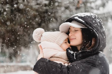 Sevgi dolu bir aile! Anne ve kız doğada karlı kış yürüyüşlerinde eğleniyor, gülüyor ve eğleniyorlar. Buz mevsimi.