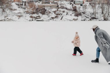 Sevgi dolu bir aile! Anne ve kız doğada karlı kış yürüyüşlerinde eğleniyor, gülüyor ve eğleniyorlar. Buz mevsimi.