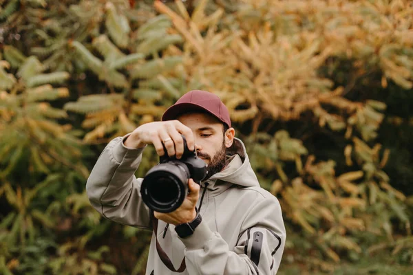 年轻的高加索男性摄影师在秋天的公园拍照 — 图库照片