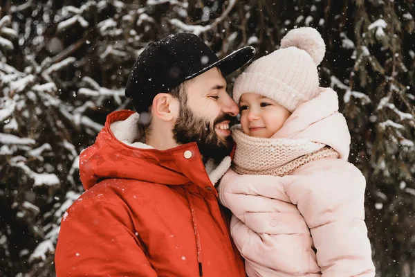Genç şık sakallı baba ve küçük kızı kış tatilinde. Baba oğlunu parka geri götürüyor. Mutlu, neşeli bir aile. Mutlu, neşeli bir aile.