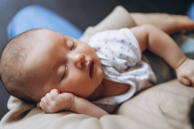 Sevgi dolu anne, yeni doğmuş bebeğini evde taşıyor. Elinde uyuyan mutlu bebek portresi var. Anne 1 aylık kızına sarılıyor..