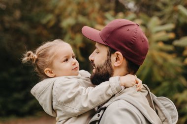 Mutlu baba ve kızı güzel bir sonbahar parkında yürürken oynuyorlar. İdeal hafta sonu babası ve küçük kızı, sonbahar havası.