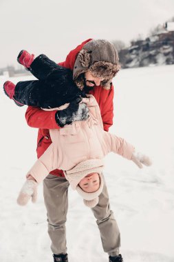 Sevgi dolu bir aile! Babası ve bebeği dışarıda oynuyorlar ve sarılıyorlar. Küçük çocuk ve babası karlı bir kış yürüyüşünde. Uzun zamandır beklenen ilk kar yağışının konsepti. Boşluğu kopyala