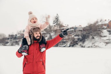 Sevgi dolu bir aile! Babası ve bebeği dışarıda oynuyorlar ve sarılıyorlar. Küçük çocuk ve babası karlı bir kış yürüyüşünde. Uzun zamandır beklenen ilk kar yağışının konsepti. Boşluğu kopyala